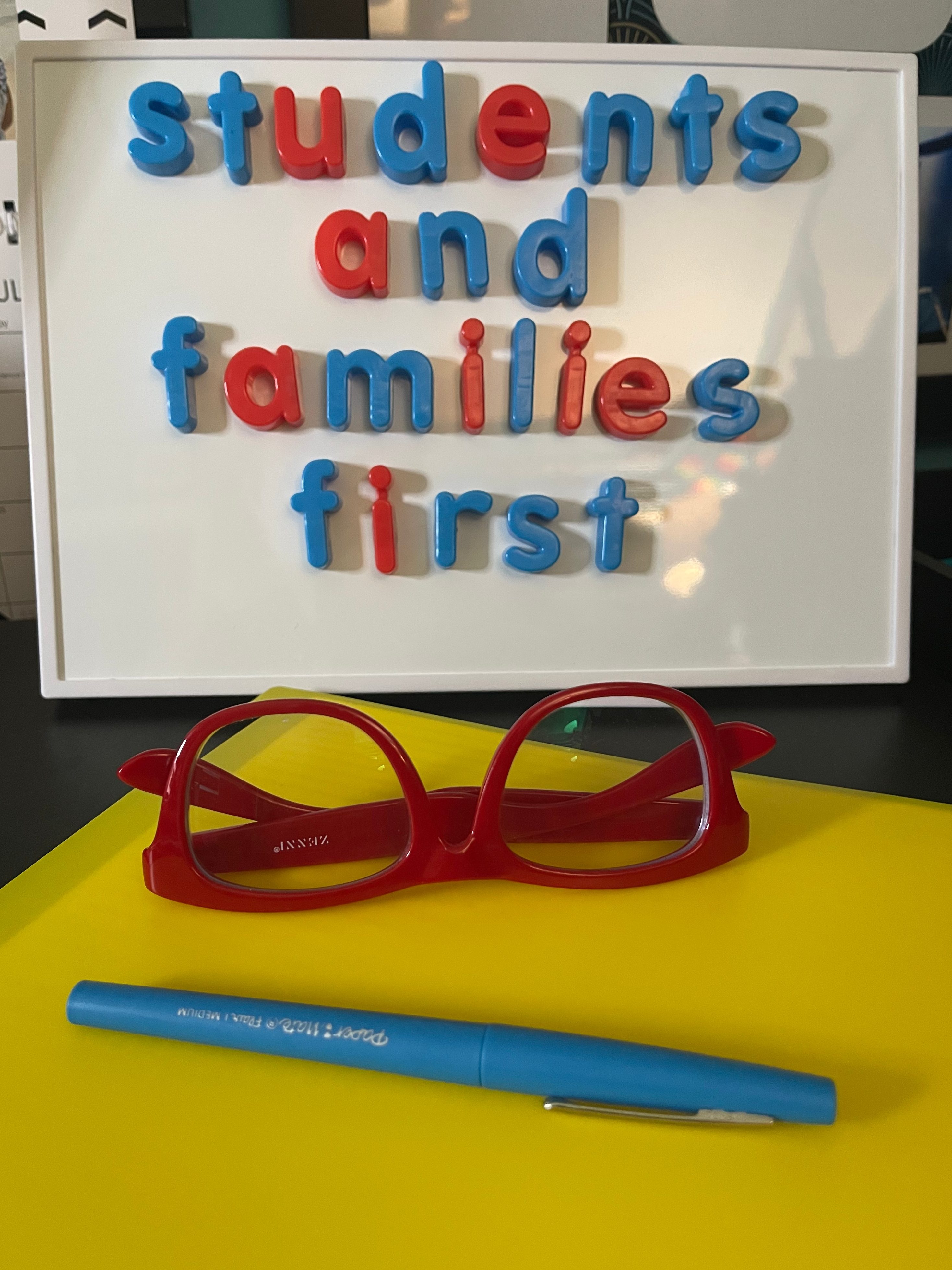 White board that says "Students and Families First" in magnetic letters.